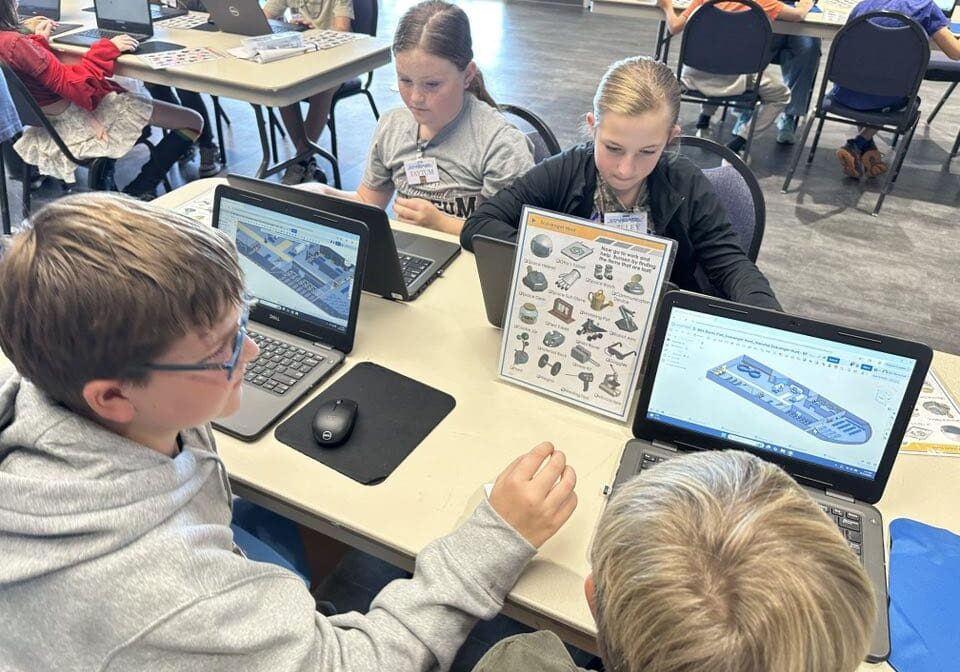 Students working on 3D models at laptops during a CAD activity.